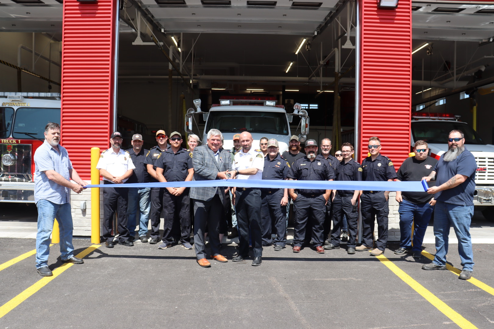 A group of people stand in front of a new building in Springhill preparing to cut a ribbon to officially open the structure.